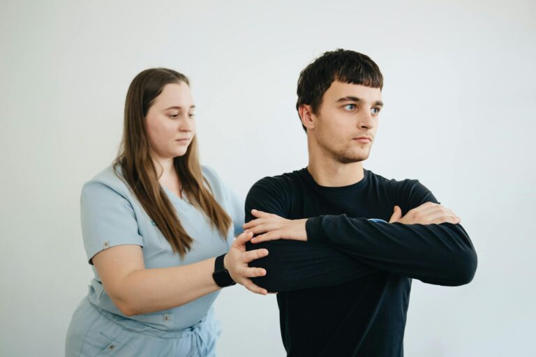 A physiotherapist assists a patient with arm exercises in a clinical setting.